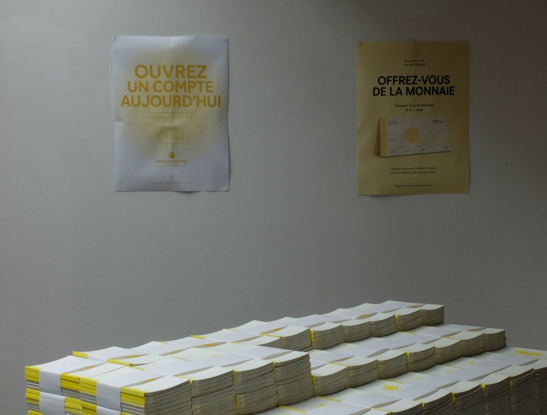 Le magot&nbsp;: des piles de chéquiers blancs et jaunes sous deux affiches de la banque